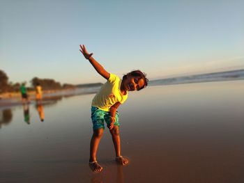 Full length of girl with arms outstretched enjoying on shore at beach