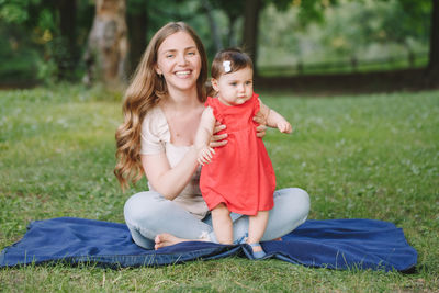 Mother and daughter sitting on grass
