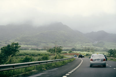 Cars on road by mountains against sky