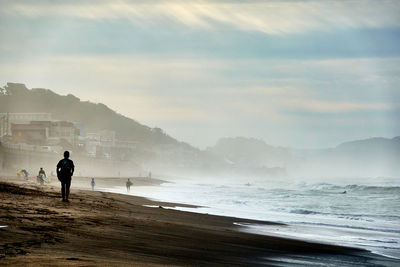 Silhouette man standing on beach against sky