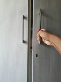 Cropped hand of person opening cabinet door