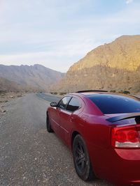 Car on road by mountains against sky