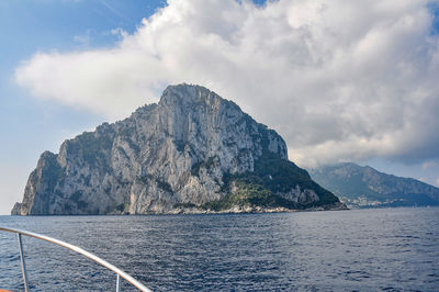 Scenic view of sea by mountains against sky