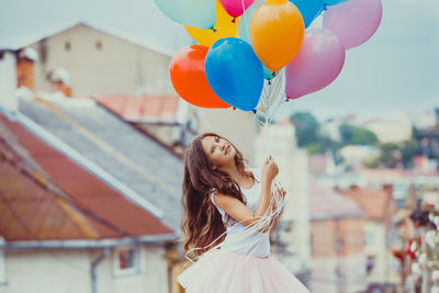 Portrait of smiling teenage girl holding balloons outdoors