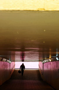 Rear view of man walking at underground walkway