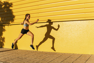 Full length of woman running on wall