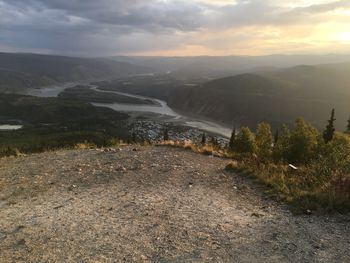 Scenic view of river amidst mountains against sky during sunset