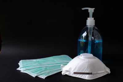 Close-up of white bottle on table against black background