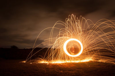 Man with wire wool standing on field at night