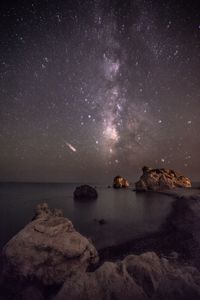 Rocks on sea against sky at night