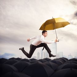 Man holding umbrella standing against sky