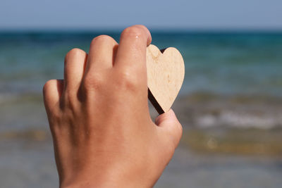 Midsection of person holding sea against sky