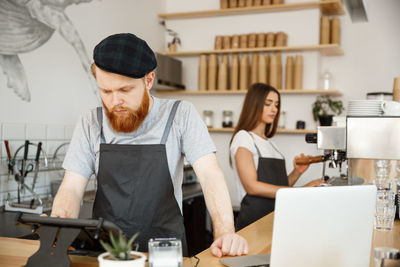 Side view of young man using mobile phone while standing in office