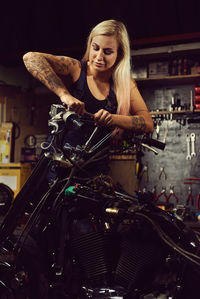 Woman repairing motorcycle at workshop