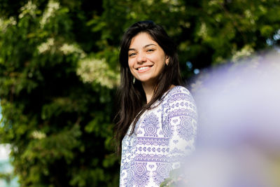 Portrait smiling young woman standing against tree