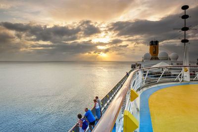 People at sea shore against sky during sunset