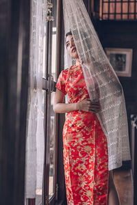 Midsection of woman standing by red window