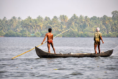 People in boat sailing on sea against sky