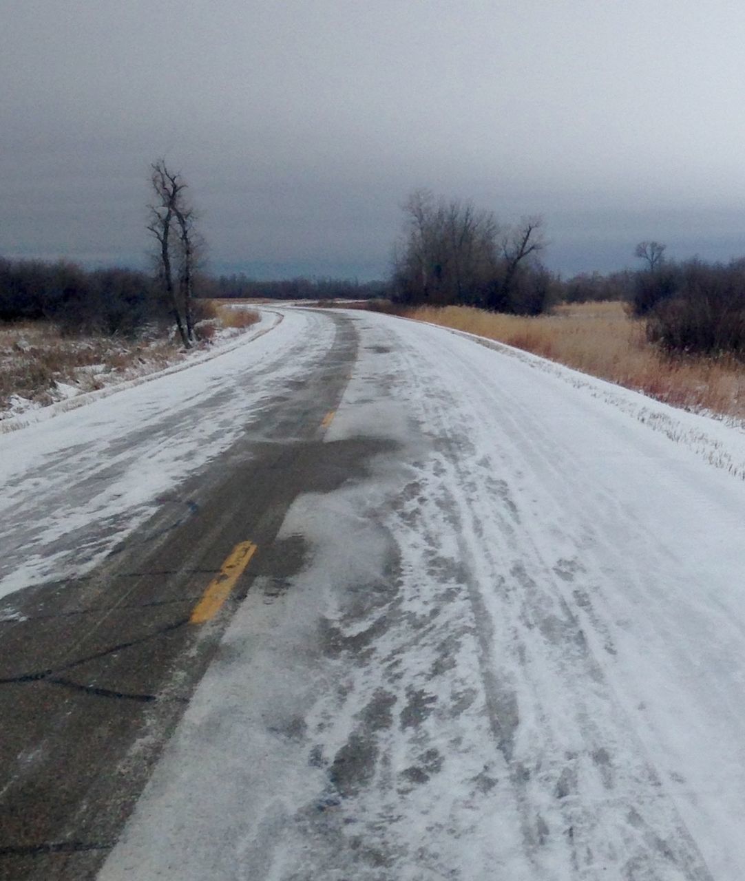 SNOW COVERED ROAD AMIDST FIELD AGAINST SKY