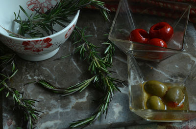 Still life with rosemary, green olives, red peperoni antipasto on gray marble