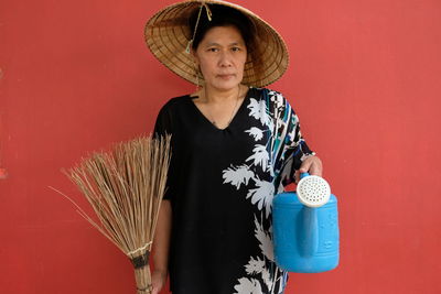 Portrait of woman standing against red wall