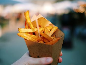 Cropped image of hand holding cone with french fries 