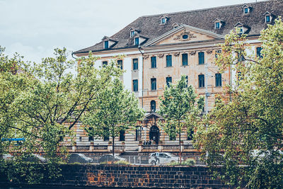 Low angle view of trees and building against sky