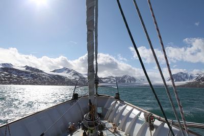 Sailboat sailing on sea by mountains against sky