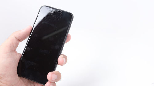 Close-up of hand holding smart phone over white background