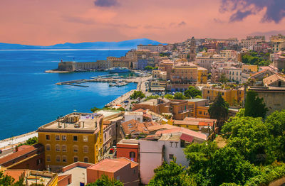 High angle view of townscape by sea against sky during sunset