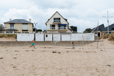 People playing on beach against buildings