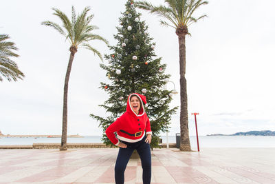 Woman standing by palm trees against sky