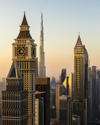 Modern buildings in dubai against sky during sunset