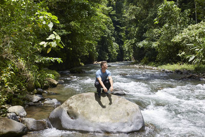 Rear view of man standing on rock in river