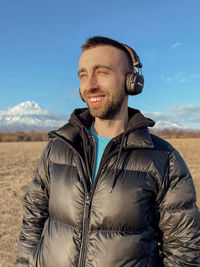 Portrait of smiling young man standing on land against sky