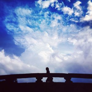 Low angle view of silhouette people against cloudy sky