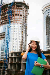 Female architect standing against incomplete building