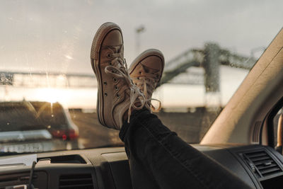 Low section of person wearing shoes on car windshield