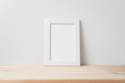 Close-up of white wooden table against wall