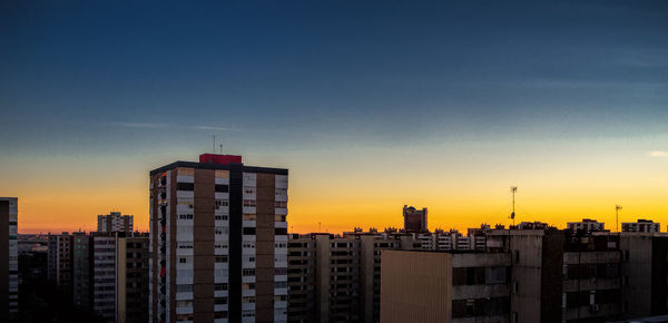 Modern buildings against sky during sunset