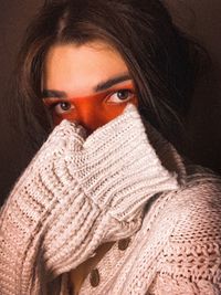 Portrait of woman wearing sweater against black
background