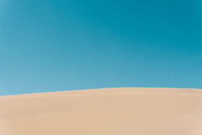 Scenic view of desert against clear blue sky