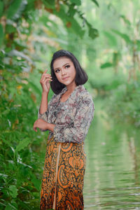 Portrait of woman standing against plants