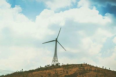 Low angle view of windmill against cloudy sky