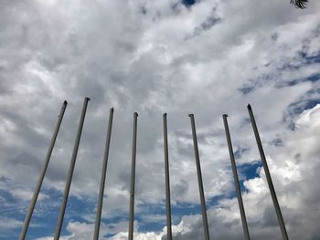Low angle view of poles against cloudy sky