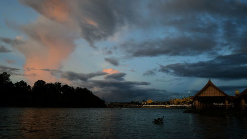 Panoramic view of lake and buildings against sky at sunset