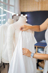 Midsection of woman holding clothes at store