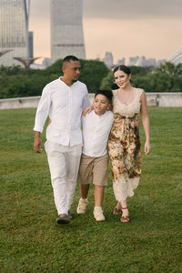 Rear view of friends standing on grassy field