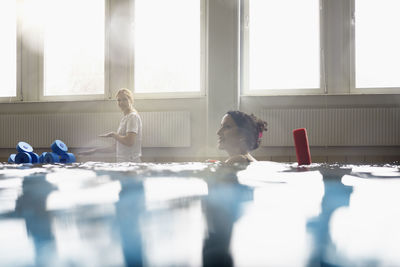 Smiling woman with noodle float in swimming pool at rehabilitation center