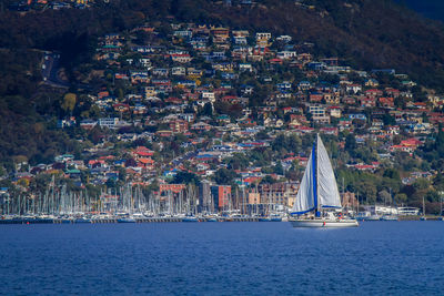 Sailboats sailing on sea by buildings in city